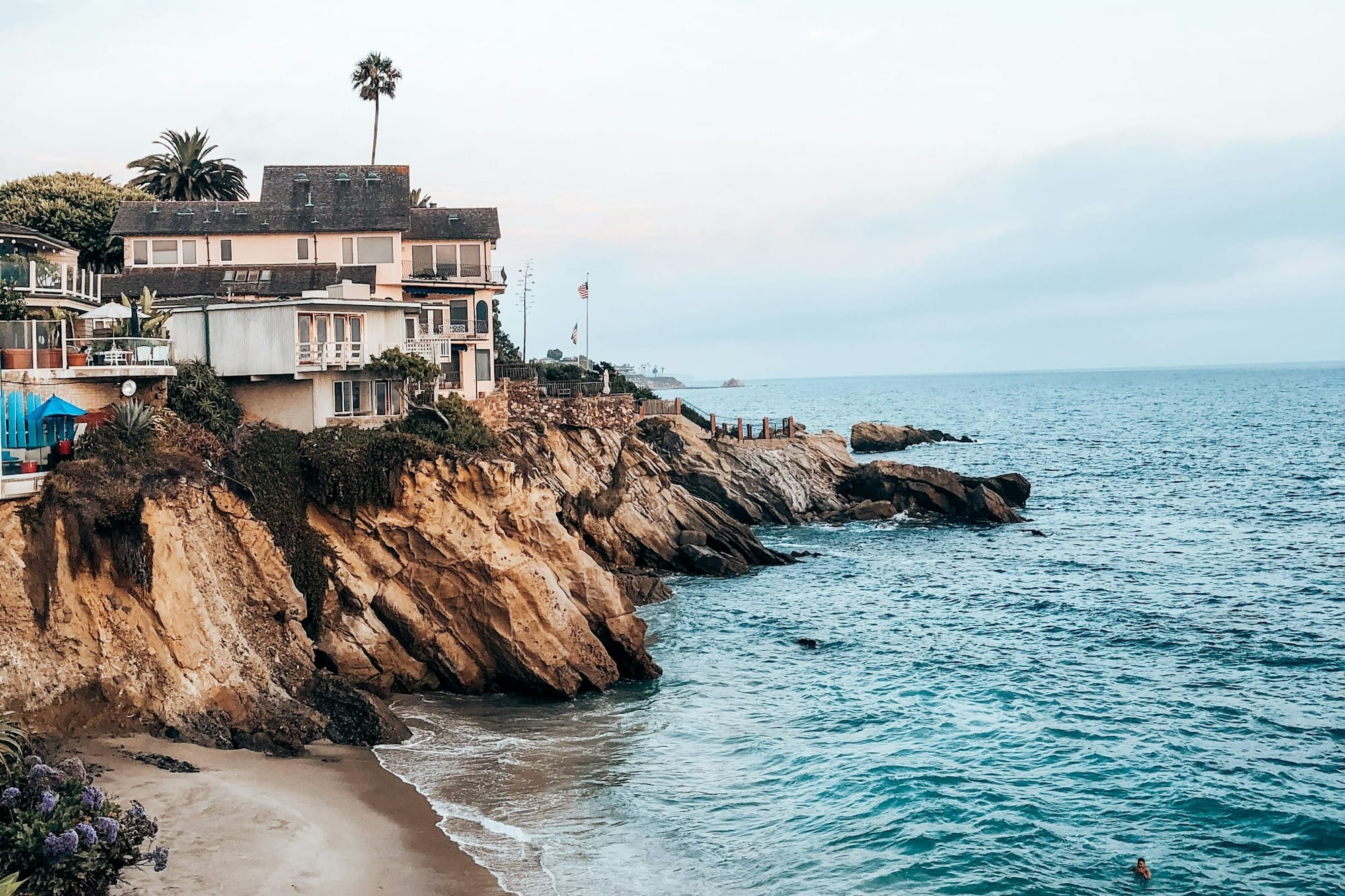 a sandy beach with houses on the cliff